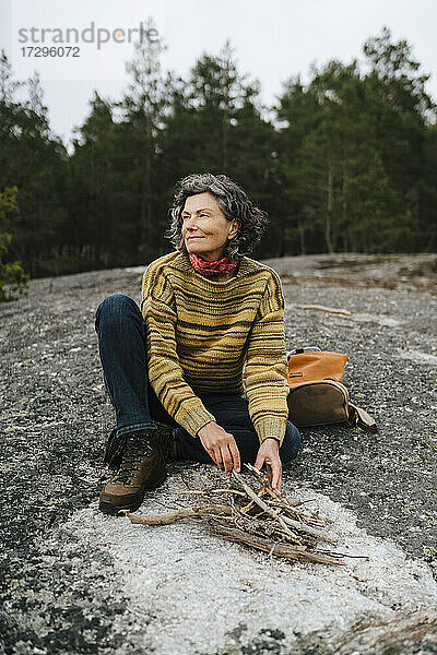Lächelnd weiblichen Forscher Vorbereitung Lagerfeuer beim Sitzen im Wald