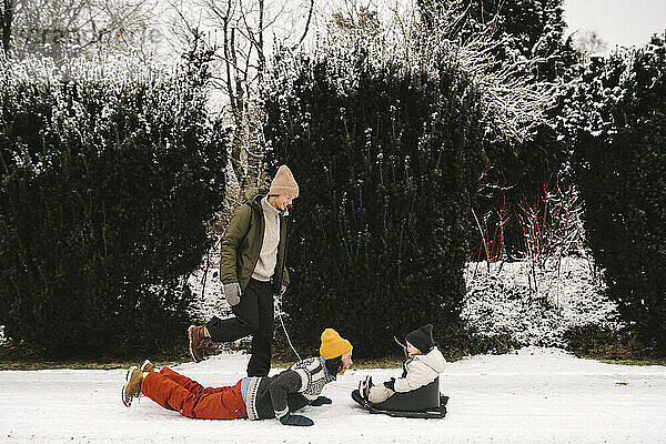 Playful Mutter liegend Blick auf Tochter von Freundin im Winter