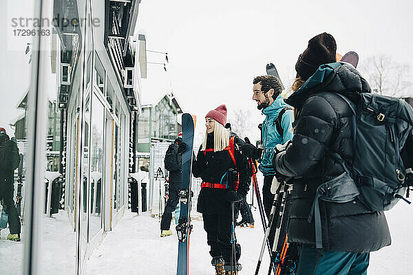 Männliche und weibliche Freunde stehen vor dem Geschäft im Winter