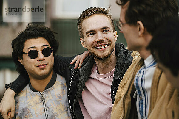 Lächelnde junge männliche Freunde im Gespräch miteinander
