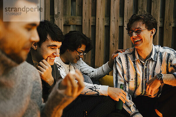 Glückliche junge männliche Freunde  die sich unterhalten  während sie ihre Freizeit auf dem Balkon verbringen