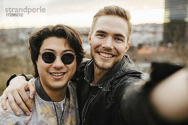 Junge männliche Freunde lächelnd während der Aufnahme selfie