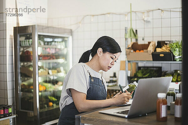 Weibliche Unternehmerin schreibt am Laptop im Geschäft