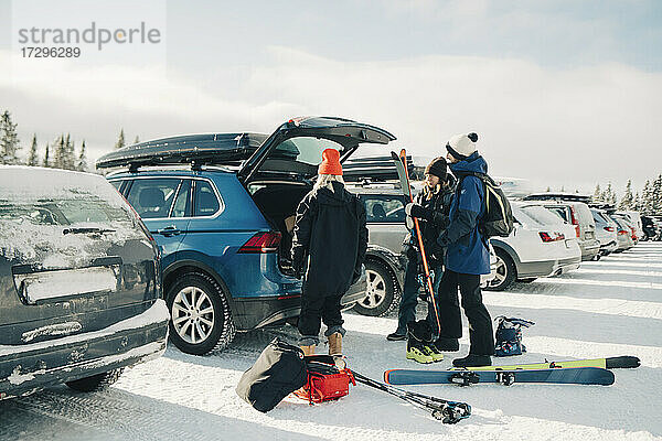 Weibliche und männliche Freunde laden Skier in Kofferraum Auto im Winter