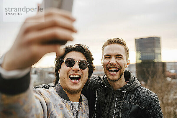 Fröhliche männliche Freunde nehmen Selfie auf Smartphone