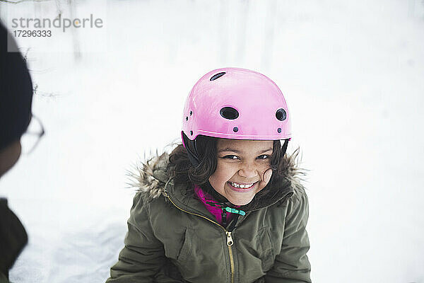 Porträt eines fröhlichen Mädchens mit rosa Helm im Winter