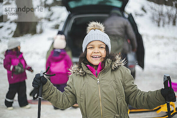 Porträt eines lächelnden Mädchens mit Skistöcken im Winter