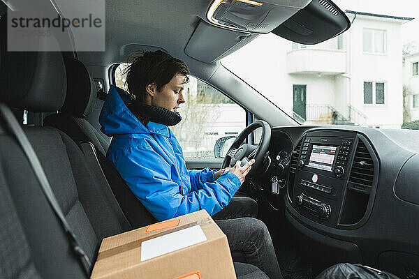 Weiblicher Fahrer  der ein Smartphone benutzt  während er im Lieferwagen sitzt