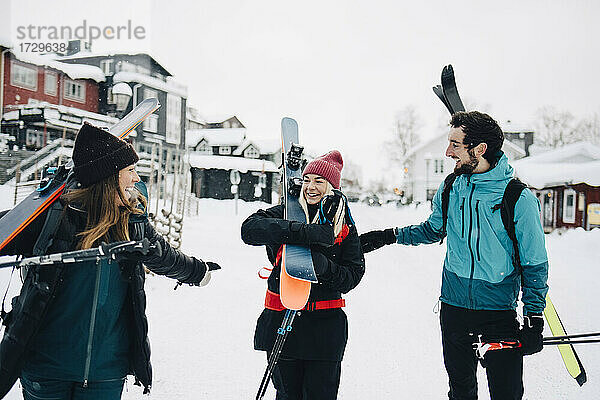 Fröhliche männliche und weibliche Freunde tragen Skier im Winter