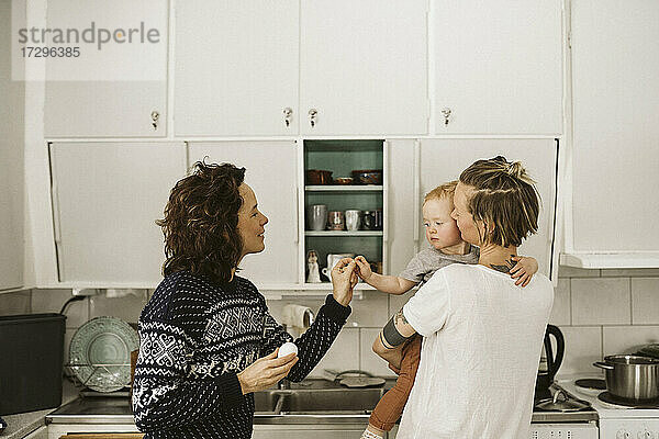 Lesbische Mütter mit Tochter in der Küche zu Hause