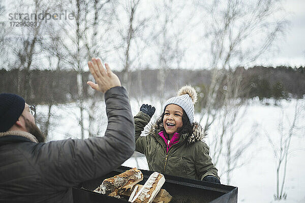 Glückliches Mädchen gibt high five zu Vater während des Winters