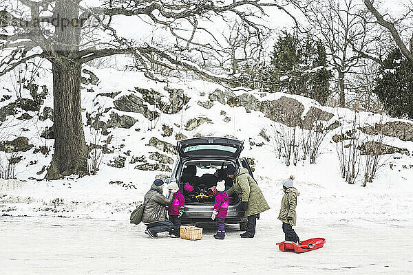 Familie im Urlaub beim Entladen des Kofferraums im Winter