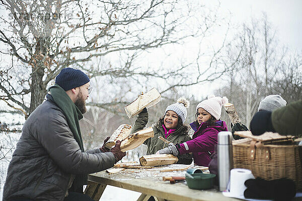 Vater und Tochter mit Brennholz sitzen am Picknicktisch im Winter