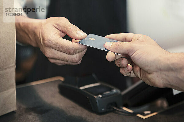 Männlicher Kunde beim Bezahlen mit Kreditkarte im Bioladen