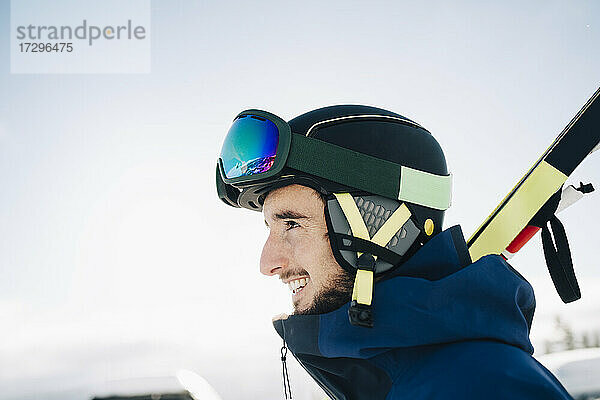 Glücklicher Mann mit Skibrille und Helm  während er gegen den Himmel wegschaut