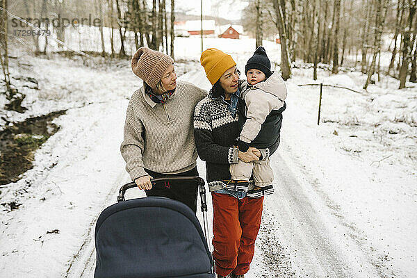 Reife Frau trägt Tochter beim Spaziergang mit Freundin auf Schnee