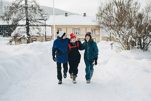 Volle Länge der glücklichen männlichen und weiblichen Freunde zu Fuß auf Schnee