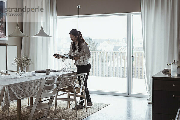 Geschäftsfrau mit digitalem Tablet im Stehen zu Hause