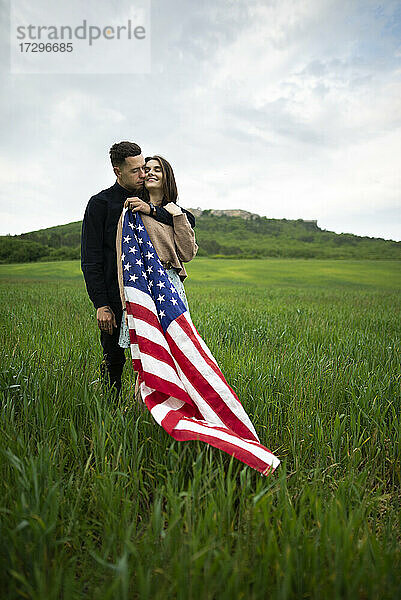 Junges Paar mit amerikanischer Flagge in einem Weizenfeld
