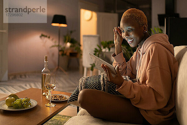Junge Frau schaut einen Film auf einem Tablet  während sie sich zu Hause entspannt