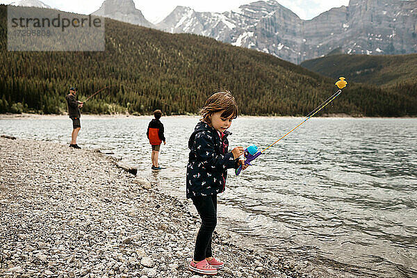 Junges Mädchen angelt mit ihrem Vater und ihrem Bruder an einem Bergsee