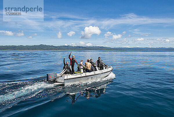 Taucher auf dem Weg zum Tauchplatz auf einem Beiboot in Raja Ampat