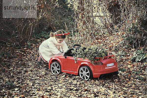 Ein Mädchen in einem Weihnachtskostüm in ihrem roten Auto