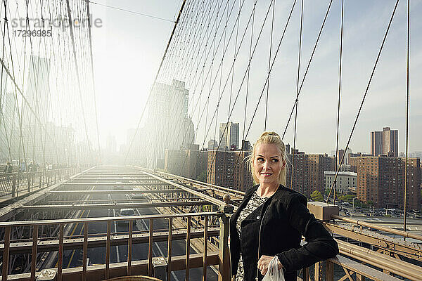 Attraktive Frau steht auf einer Brücke in einer städtischen Metropole