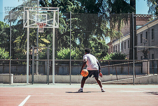 Porträt eines afroamerikanischen schwarzen Jungen  der den Ball wählt und zum Korb läuft.