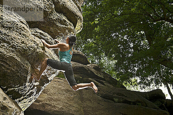 Frau beim Bouldern an den Sandsteinfelsen von Harrison's Rock in England