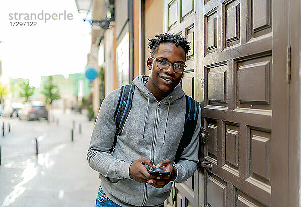 junger afrikanischer mann benutzt sein smartphone in der stadt