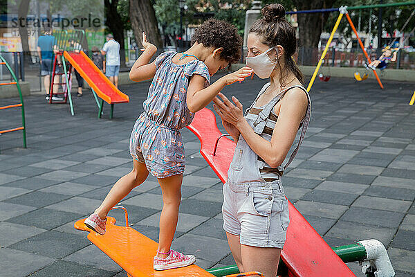 Mutter und Tochter genießen draußen auf dem Spielplatz ein neues  normales Leben.