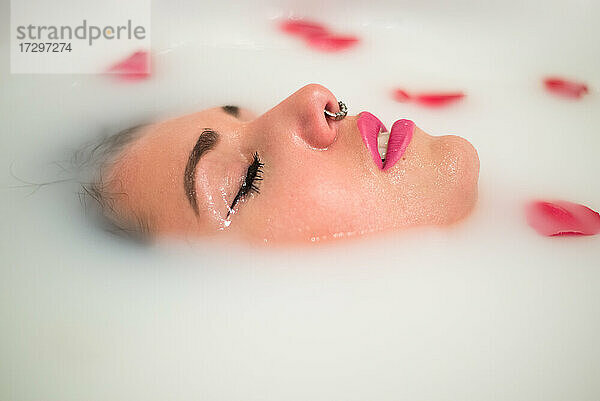 Frau entspannt sich in einer Badewanne mit Milch und Rosen