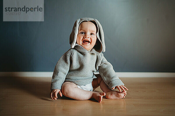 Nettes lächelndes Baby trägt einen Hasenpulli mit Ohren zu Ostern
