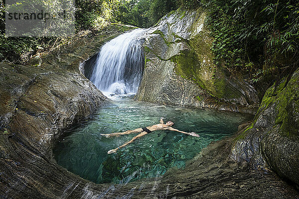 Mann genießt schönes kristallklares Wasser Regenwald Wasserfall