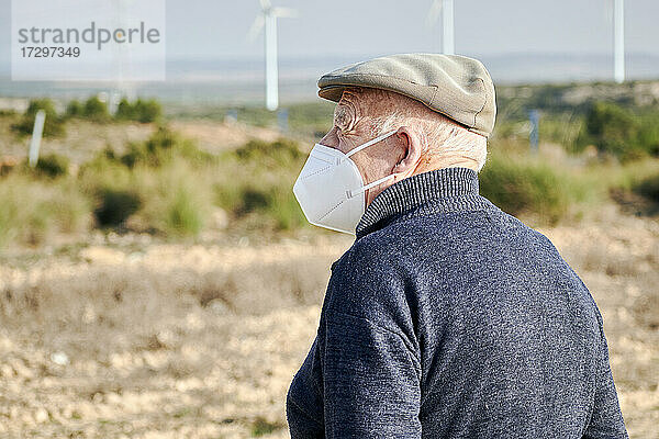 Älterer Mann mit Gesichtsmaske schaut zum Horizont