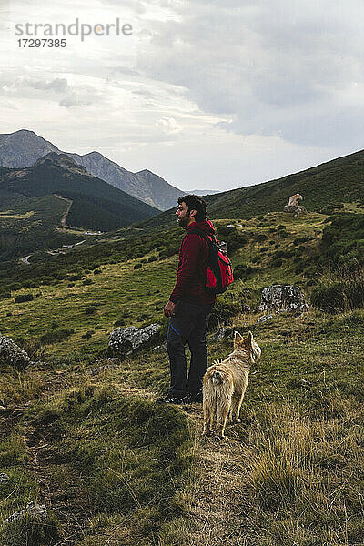 Mann  der in den Bergen mit einem Hund in den Picos de Europa spazieren geht