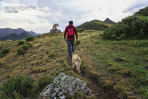 Mann beim Wandern in den Bergen mit einem Hund in den Picos de Europa