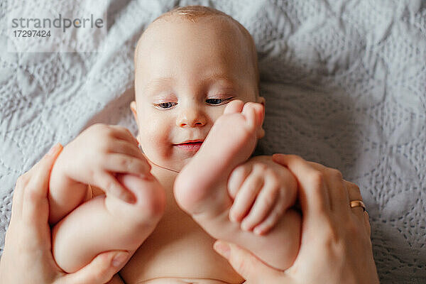 Guten Morgen Konzept. Nettes nacktes Baby inspiziert seinen Körper.