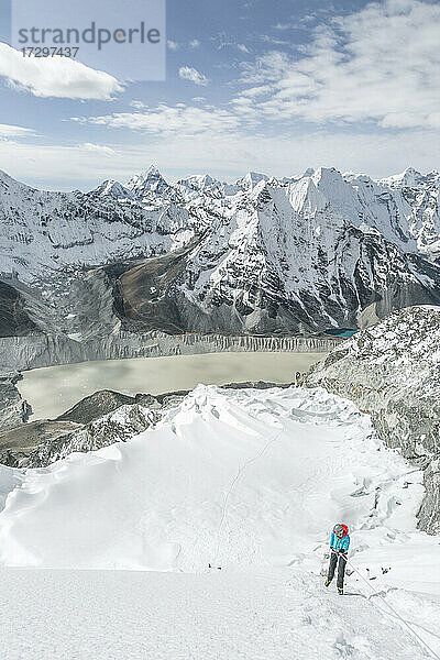 Bergsteiger in großer Berglandschaft mit blauem Himmel und Gletschersee