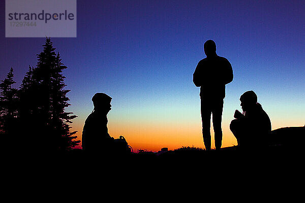 Drei Freunde genießen einen ruhigen Moment in den Bergen vor einer Wanderung.