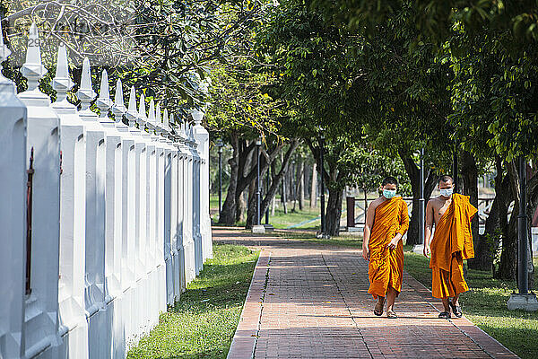 zwei buddhistische Mönche mit Gesichtsmaske in einem Tempel in Bangkok