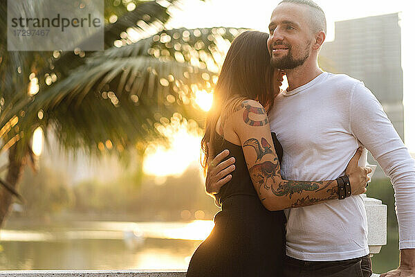 Verliebtes Paar bei Sonnenuntergang im Sonnenschein in tropischer Metropole