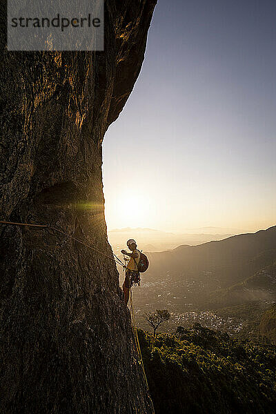 Schöner Blick auf männlichen Kletterer auf steilem felsigem Regenwaldberg
