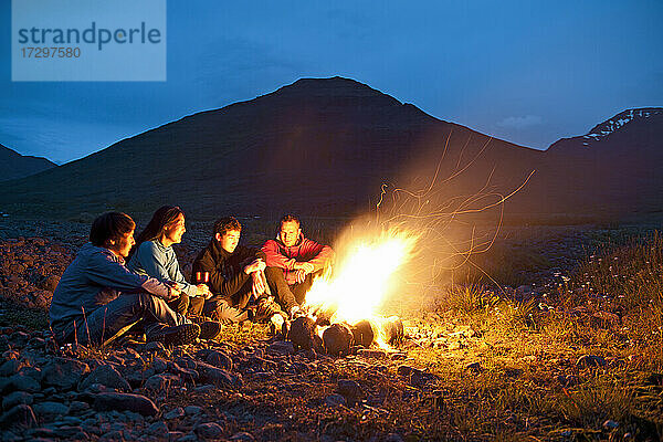 Freunde sitzen am Lagerfeuer in Island