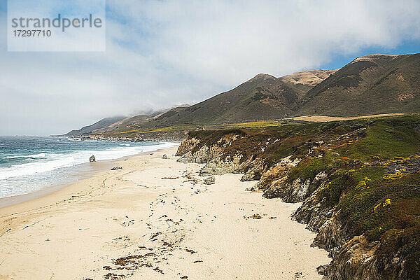 Die zerklüftete Küste von Big Sur mit Sandstrand und bewölktem Himmel