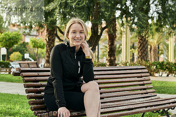 Porträt einer jungen blonden Frau  die in die Kamera lächelt  in einem Park