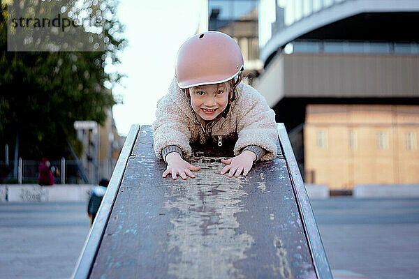 Kleines Mädchen 4 Jahre alt auf dem Skatepark lächelnd in einem Helm
