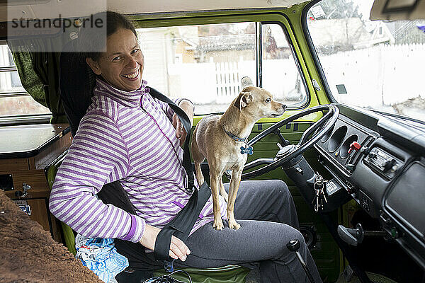 Eine Fahrerin mit Hund auf dem Schoß im VW-Wohnmobil