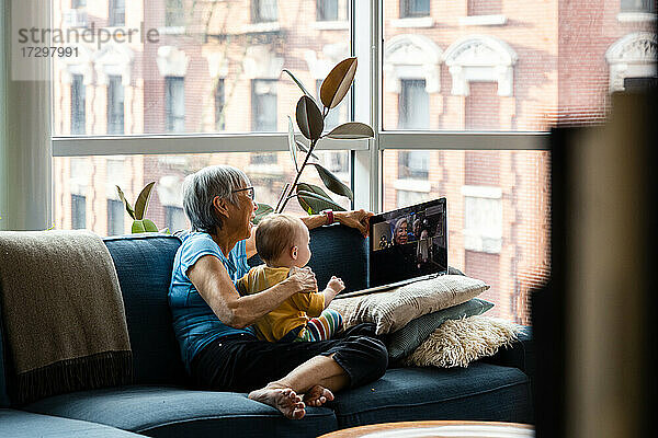 Großmutter und Enkelin benutzen Laptop für Videochat mit Verwandten
